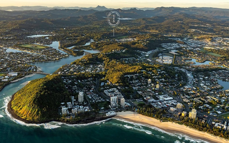 Aerial image of Burleigh beach looking along the creek and towards the mountains on the horizon. There is a range of high rises and low density developments in between bushland.