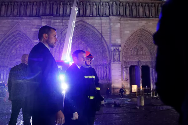 French President Emmanuel Macron speaks with firemen at the cathedral.