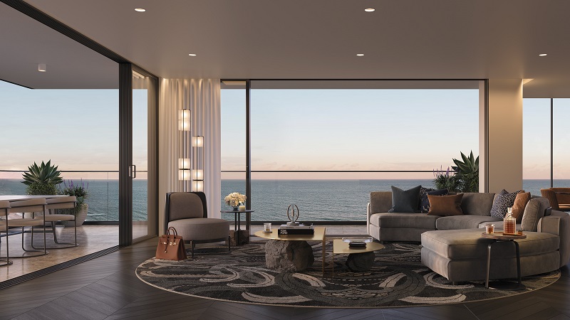 The inside of a luxurious beachside apartment on the Gold Coast has a large loungeroom with a round rug and expensive grey couches.